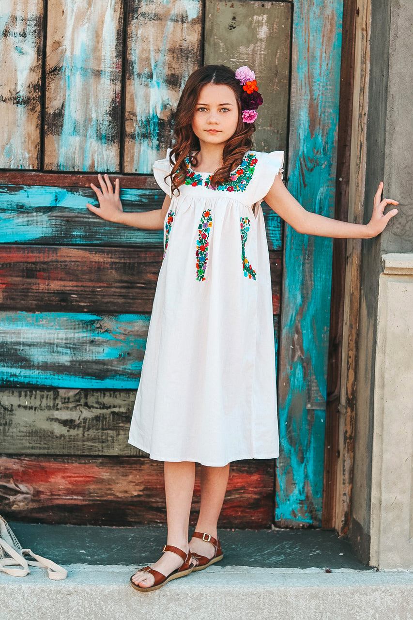 Image of a girl in a white sundress with colorful trim 